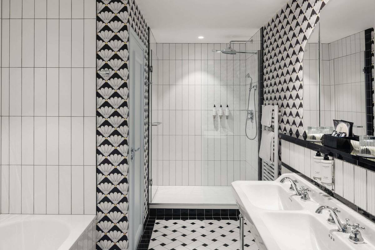 Ein modernes Badezimmer mit Schachbrettboden in Schwarz und Weiß, einer bodengleichen Dusche und einem großen Spiegel an einer Wand mit Schwarz-Weiß-Muster.