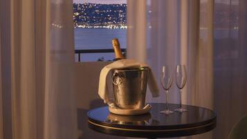 Ein Tisch mit einem Champagnerkühler und zwei Gläsern, einer Champagnerflasche und Blick auf eine Stadtlandschaft im Abendrot.
