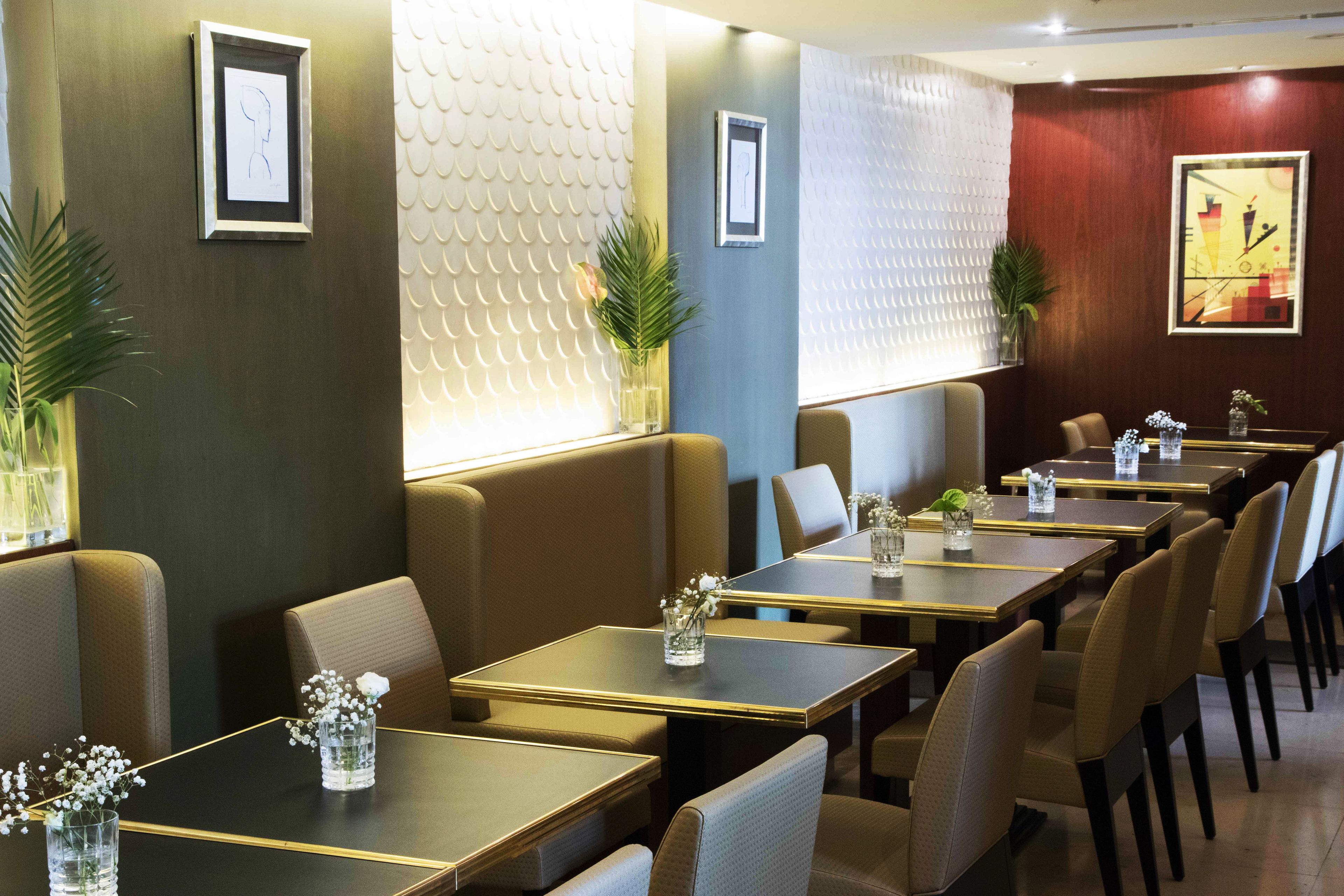 A restaurant with booths and tables, each with a vase of flowers and a glass of water.