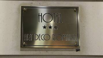 A metallic sign with the text "HOTEL ART DECO ROMA" and three stars.