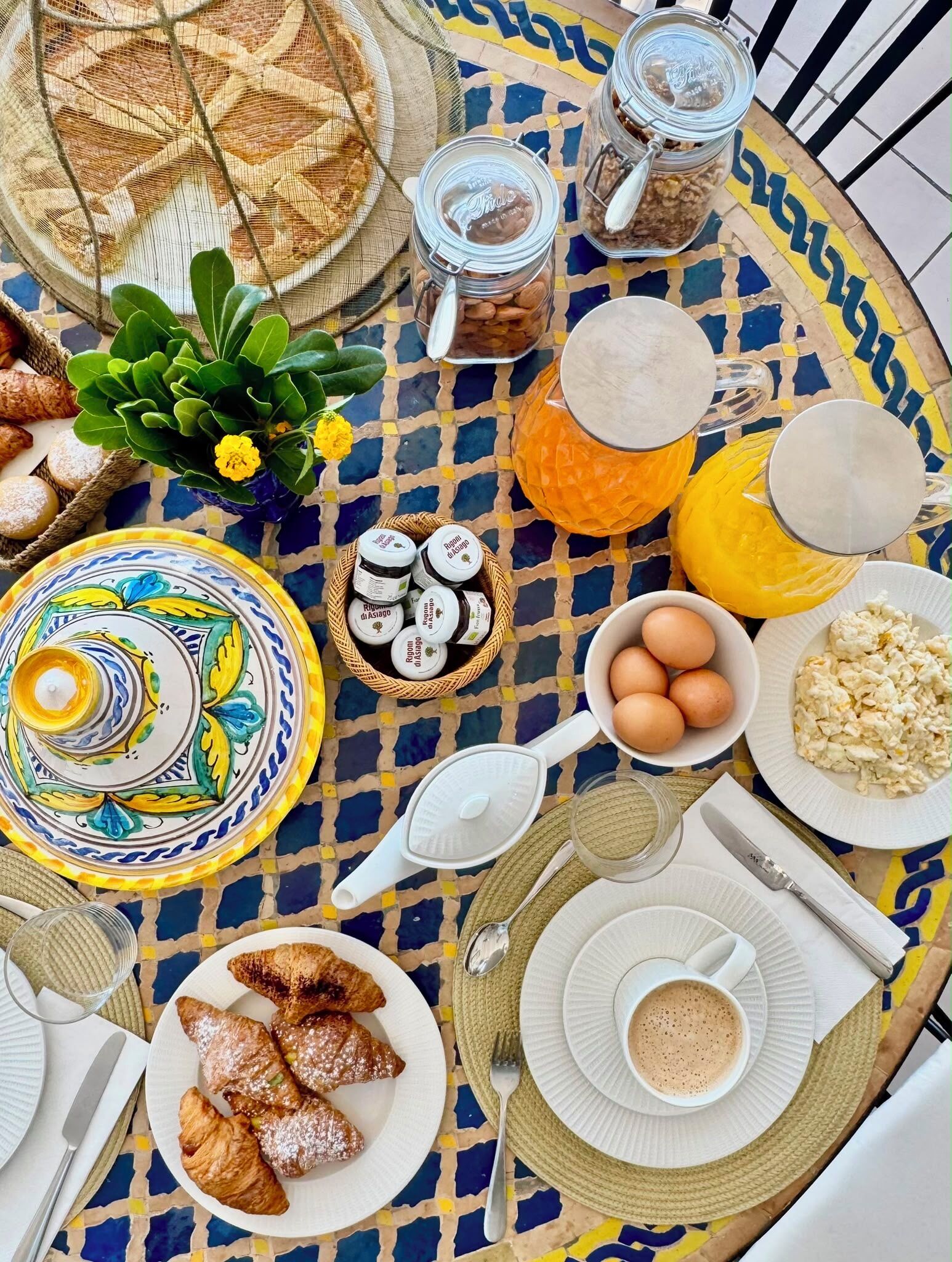 Una mesa con alimentos, entre ellos croissants, huevos y una taza de café.
