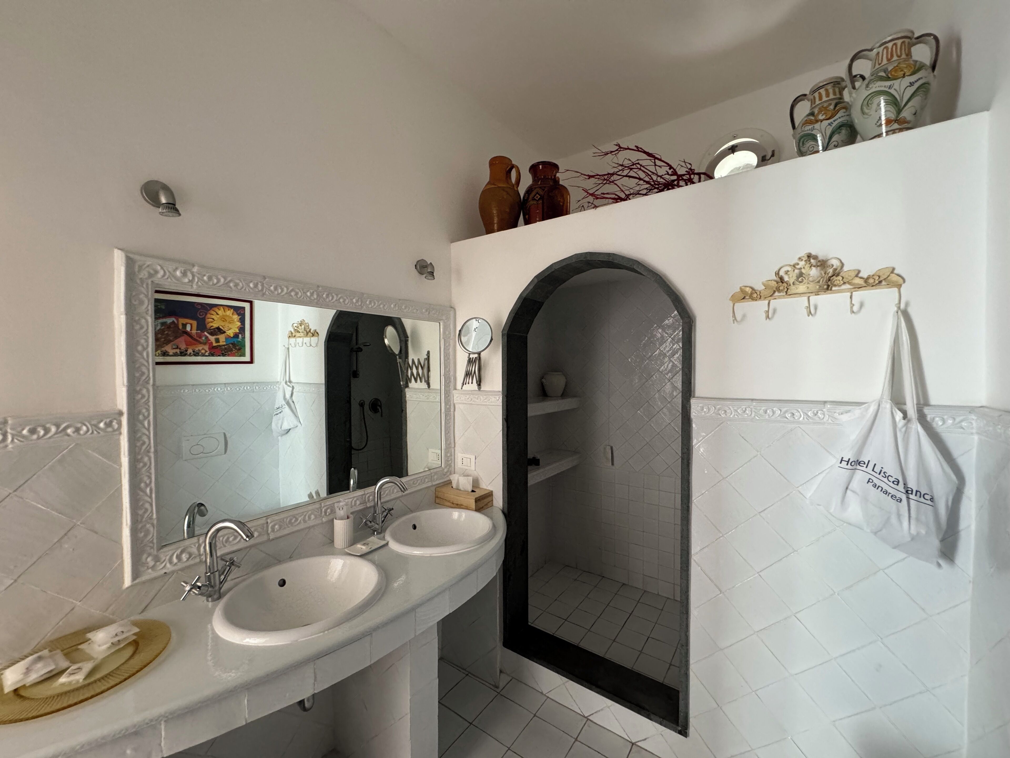 A modern bathroom with two sinks, a shower, and a vanity with decorative items.