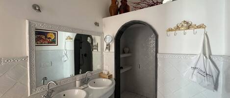 A modern bathroom with two sinks, a shower, and a vanity with decorative items.