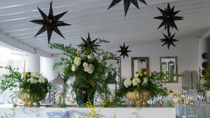 Un espace intérieur décoré avec des luminaires suspendus en forme d’étoile, des compositions florales et un plafond blanc.