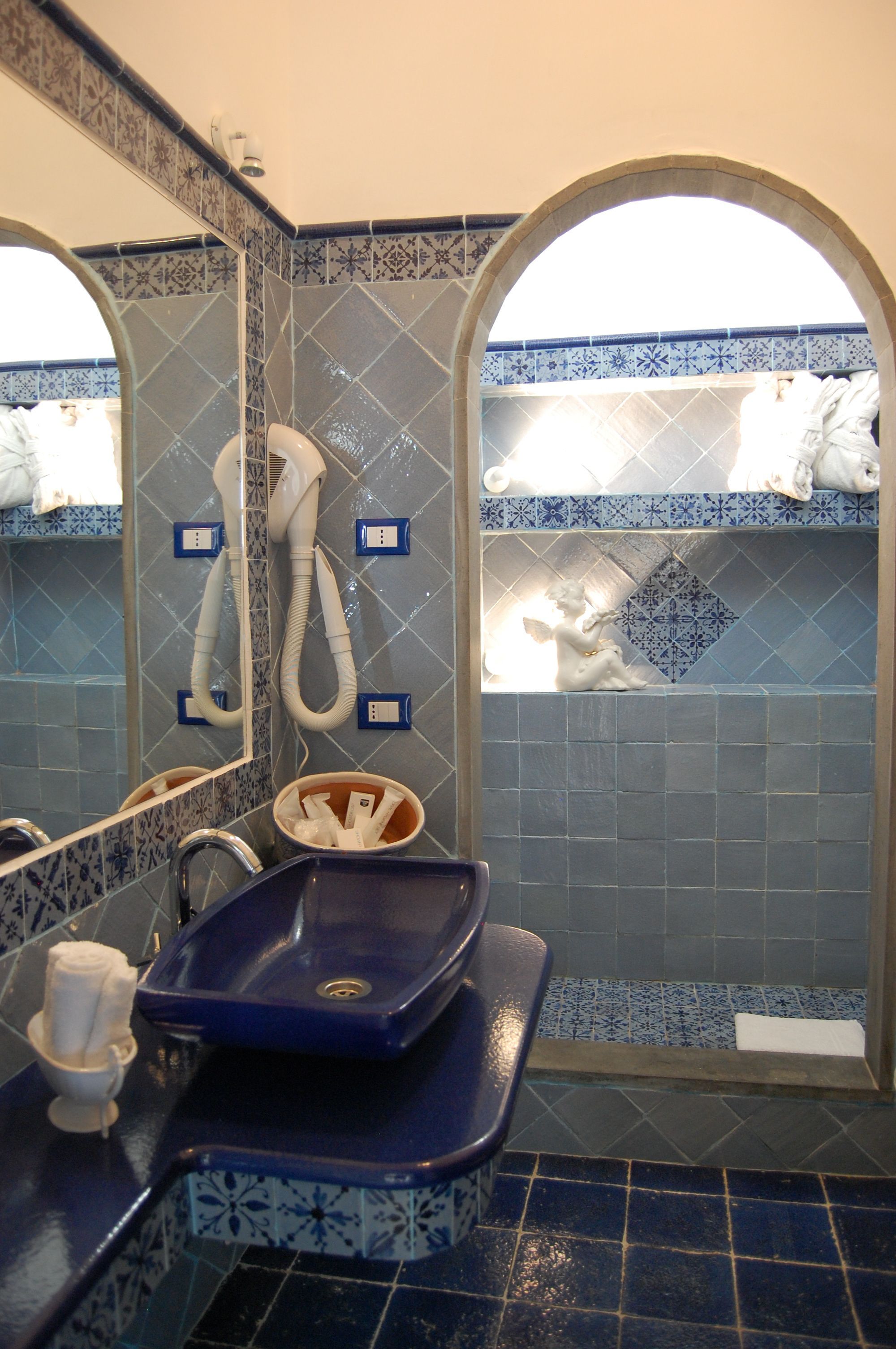 Un baño con un lavabo azul, un espejo y un perchero para toallas.