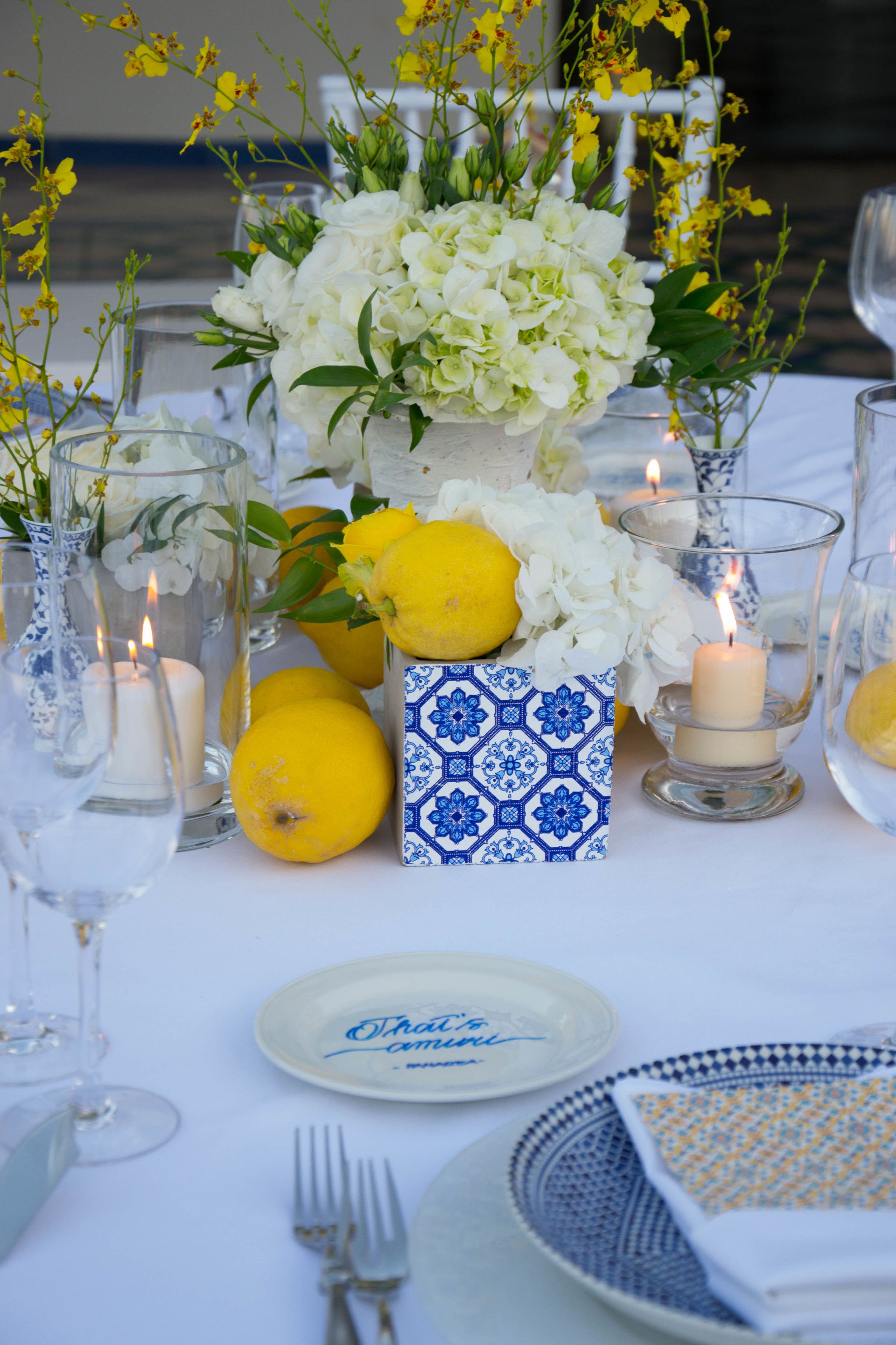 A table set with white flowers, candles, and lemons.