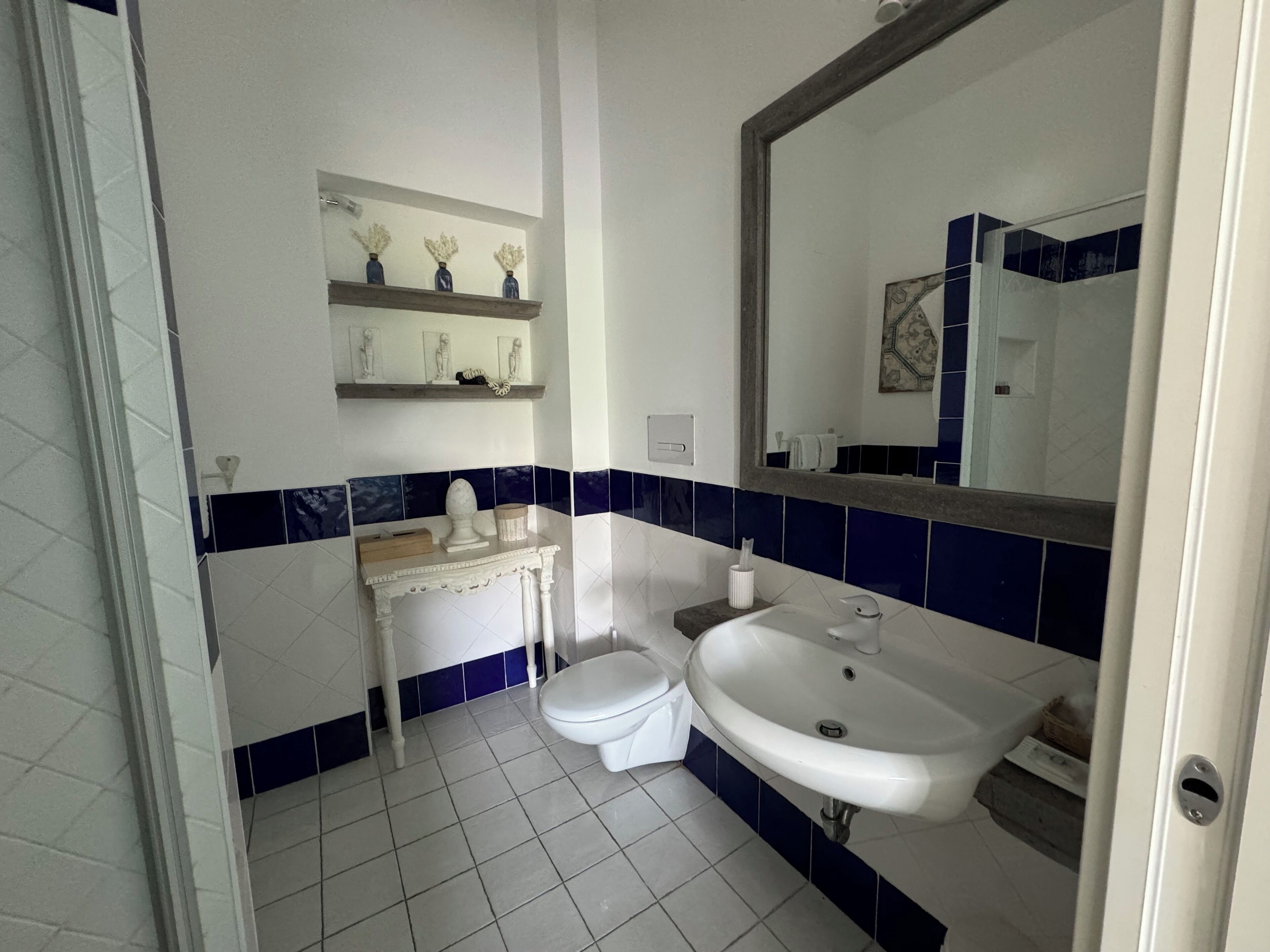 A bathroom with a white sink, toilet, and vanity. There are decorative items on the vanity and a mirror above the sink.