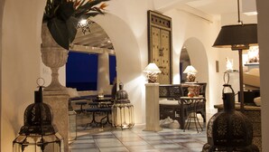 Un intérieur agrémenté d’une porte en arc donnant sur un espace repas, avec des tables, des chaises et des lanternes décoratives.