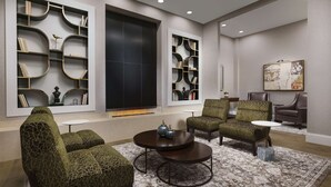 Un salon moderne comprenant un canapé d’angle, deux fauteuils, une table basse et des étagères intégrées.