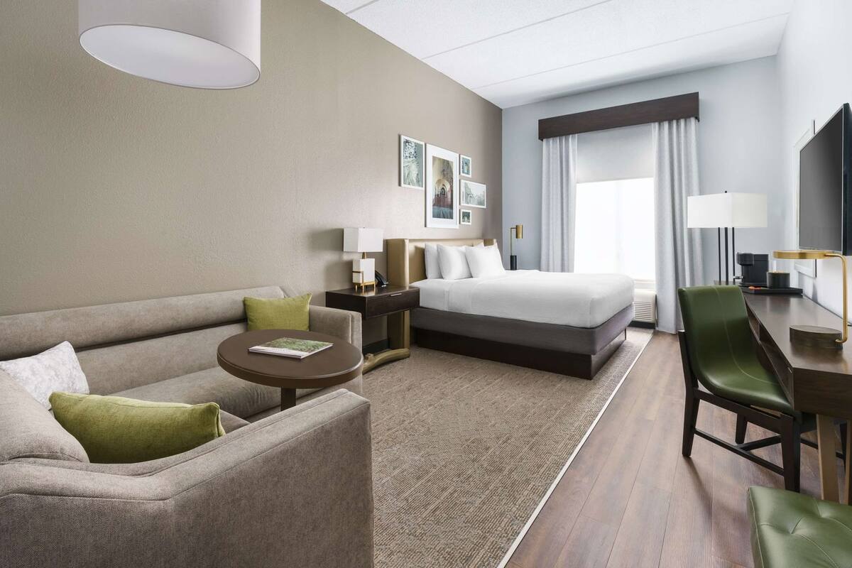 Una habitación de hotel con cama, sofá, escritorio, silla y televisor.