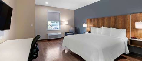 Une chambre d’hôtel avec un lit, un bureau, une chaise, une télévision et une fenêtre donnant sur un paysage agréable.