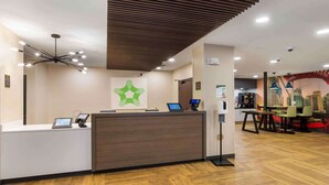A reception desk with a modern design, a digital display, and a logo on the wall.