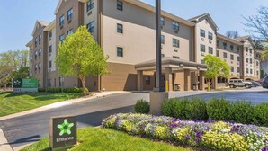 A multi-story hotel with a beige facade, a landscaped entrance area with colorful flowers, and a sign indicating the entrance.