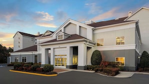A modern hotel with a two-story structure, a covered entrance, and a parking lot.