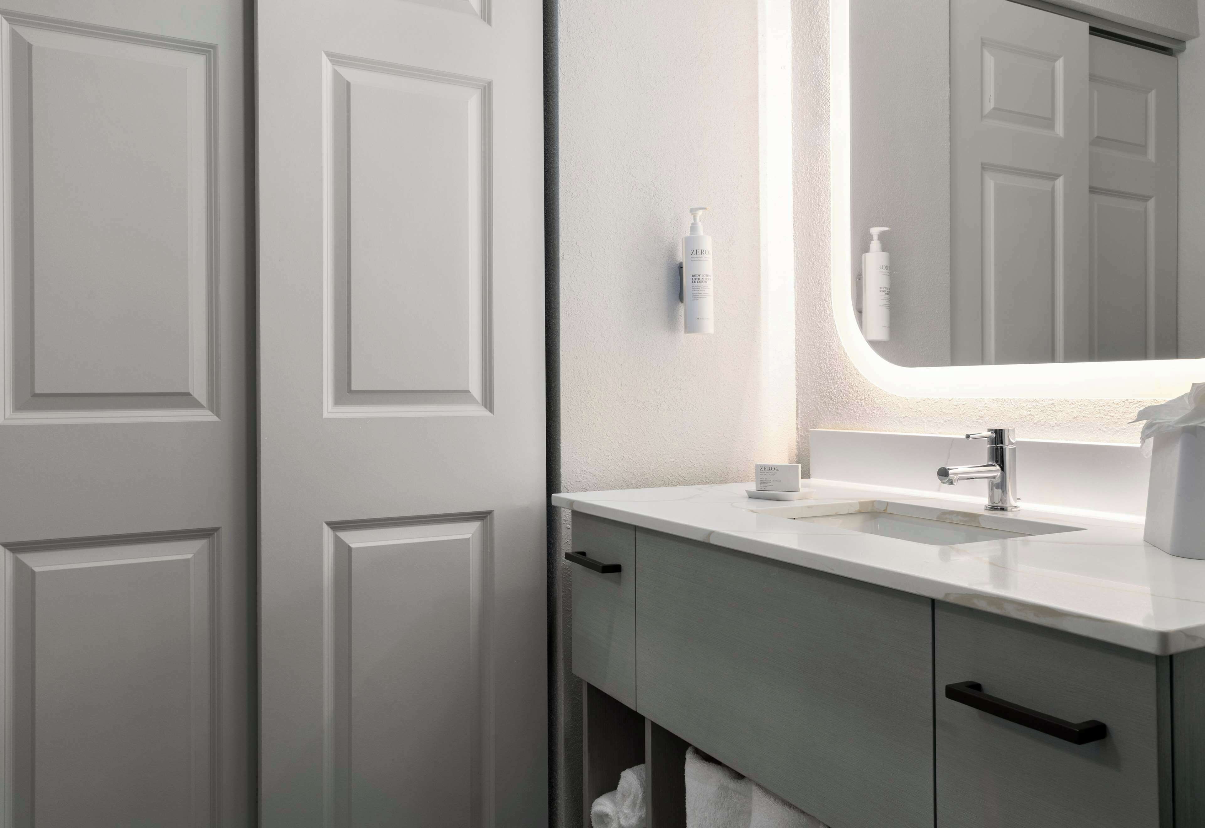 Une salle de bain avec un lavabo blanc, un miroir et un porte-serviettes.