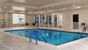 A large indoor swimming pool with clear blue water, surrounded by tiled walls and a ceiling with recessed lighting.
