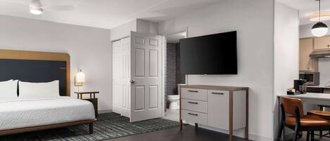 Habitación de hotel moderna con cama, escritorio, silla, televisor y baño.