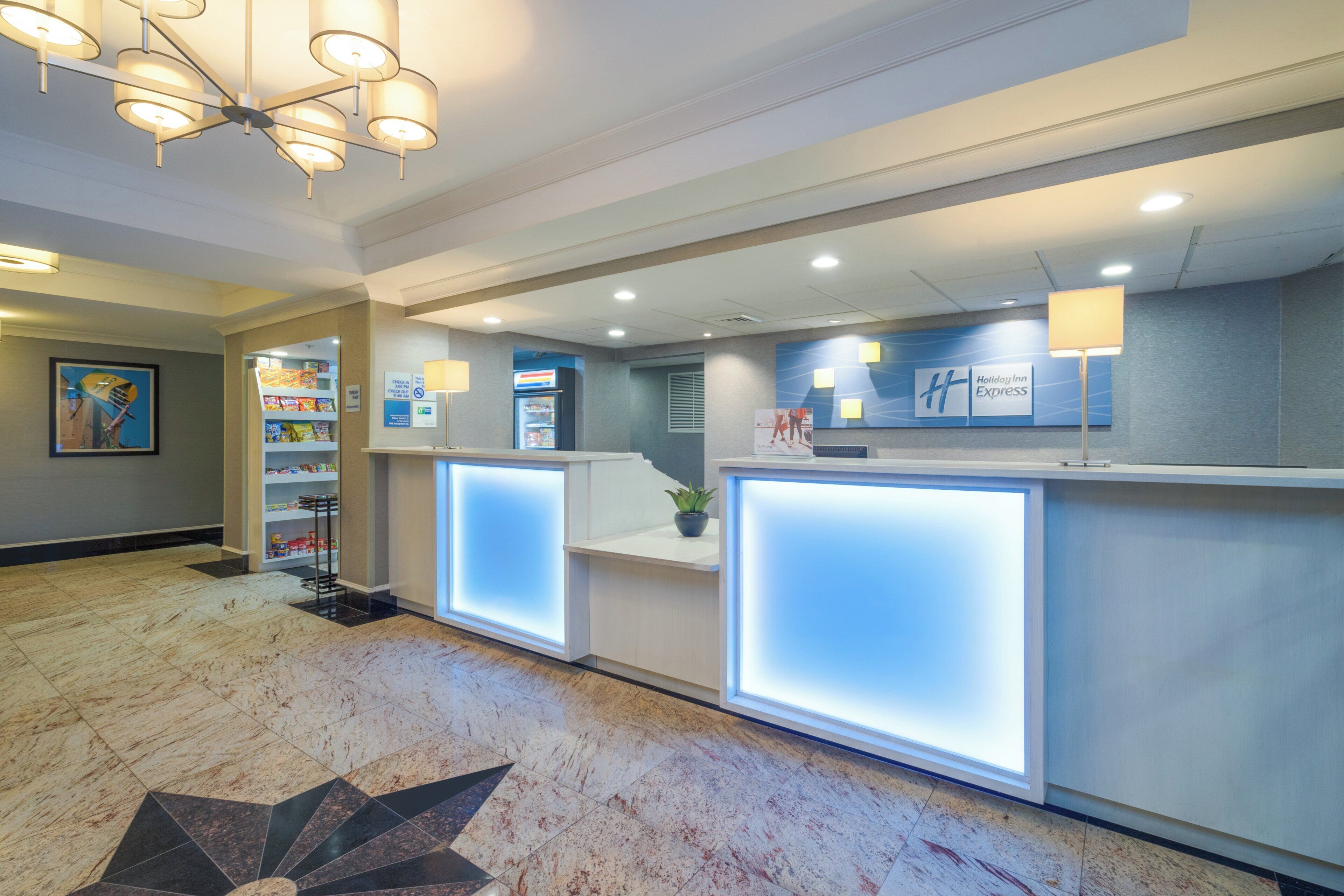 Et moderne hotelreception med skranke, selvbetjeningsautomat og et skilt monteret på væggen.
