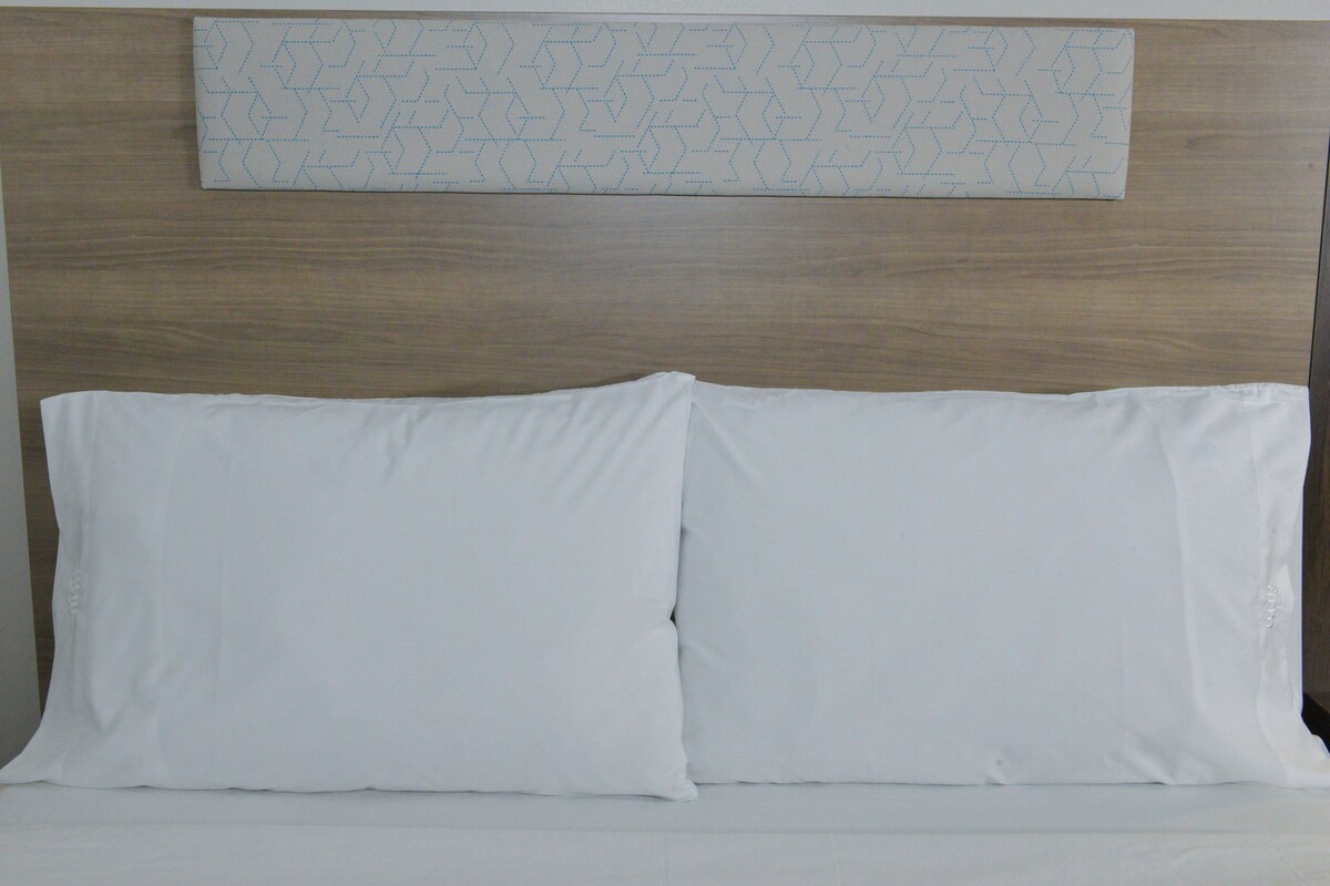 A bed with two white pillows and a wooden headboard.