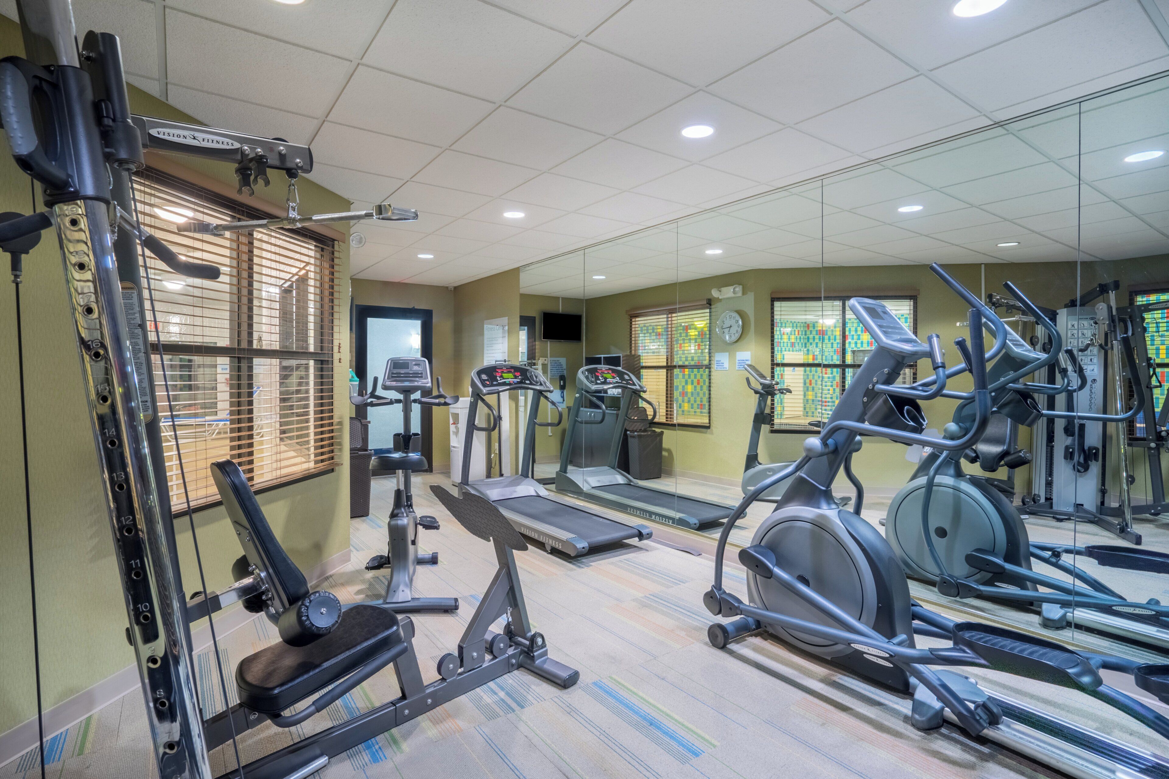 A gym with various exercise equipment including treadmills, elliptical machines, and weight machines.