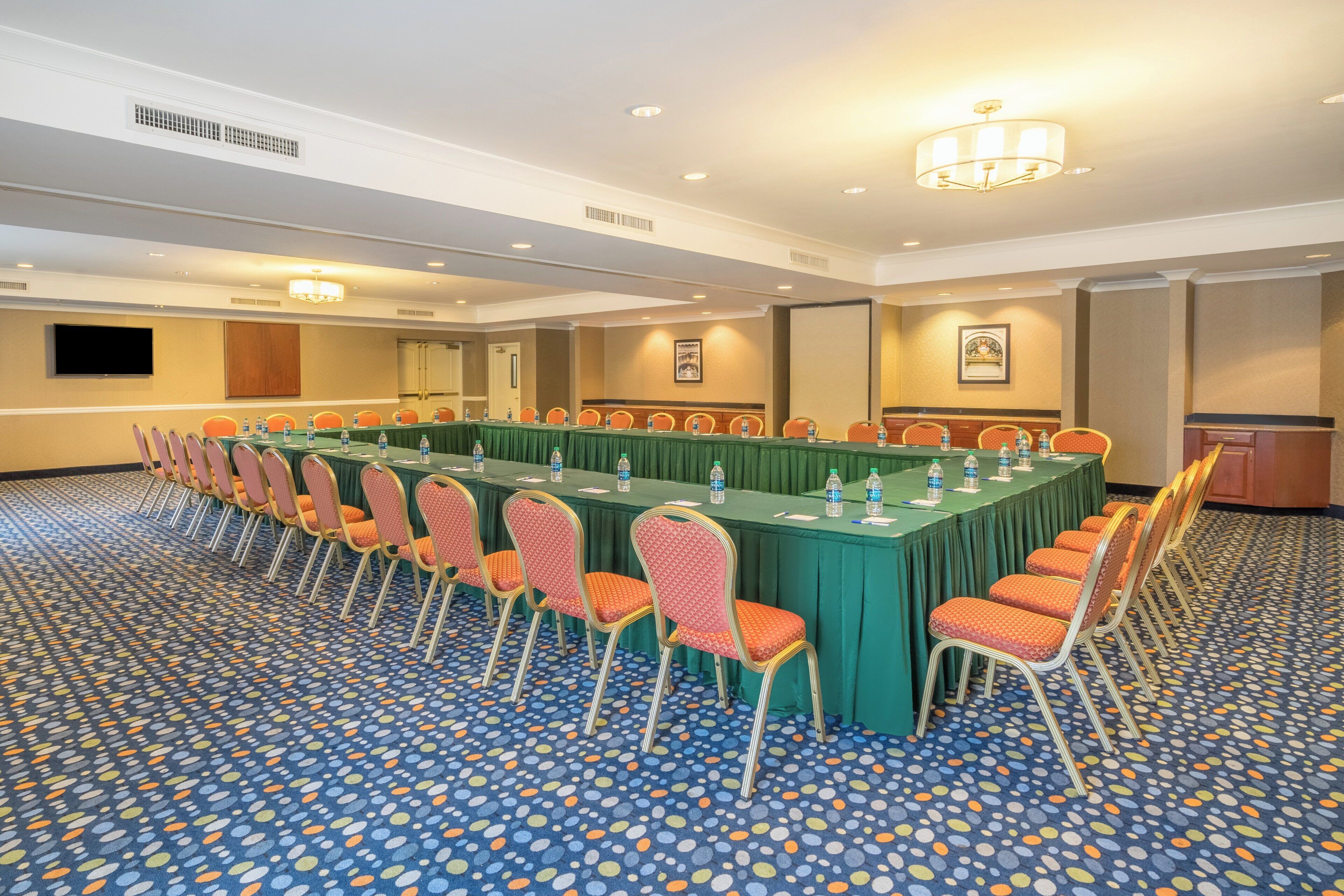 A conference room with a long table, chairs, and a patterned carpet.