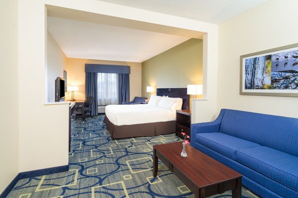 A hotel room with a bed, a blue sofa, a desk, and a TV. - Holiday Inn Express Hotel & Suites Easton by IHG (Easton)