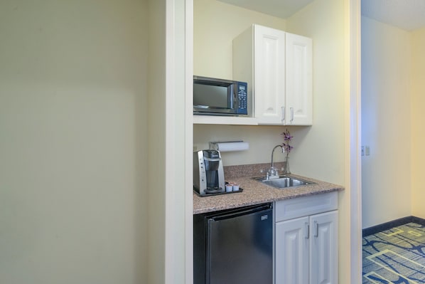 Una kitchenette compacta con microondas, cafetera y lavavajillas.