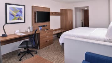 Une chambre d’hôtel comprenant un lit, un bureau avec une chaise, une télévision, une armoire et un tableau encadré au mur.
