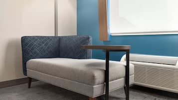 Una habitación con sofá, una mesa, un calentador portátil y una ventana con persianas.