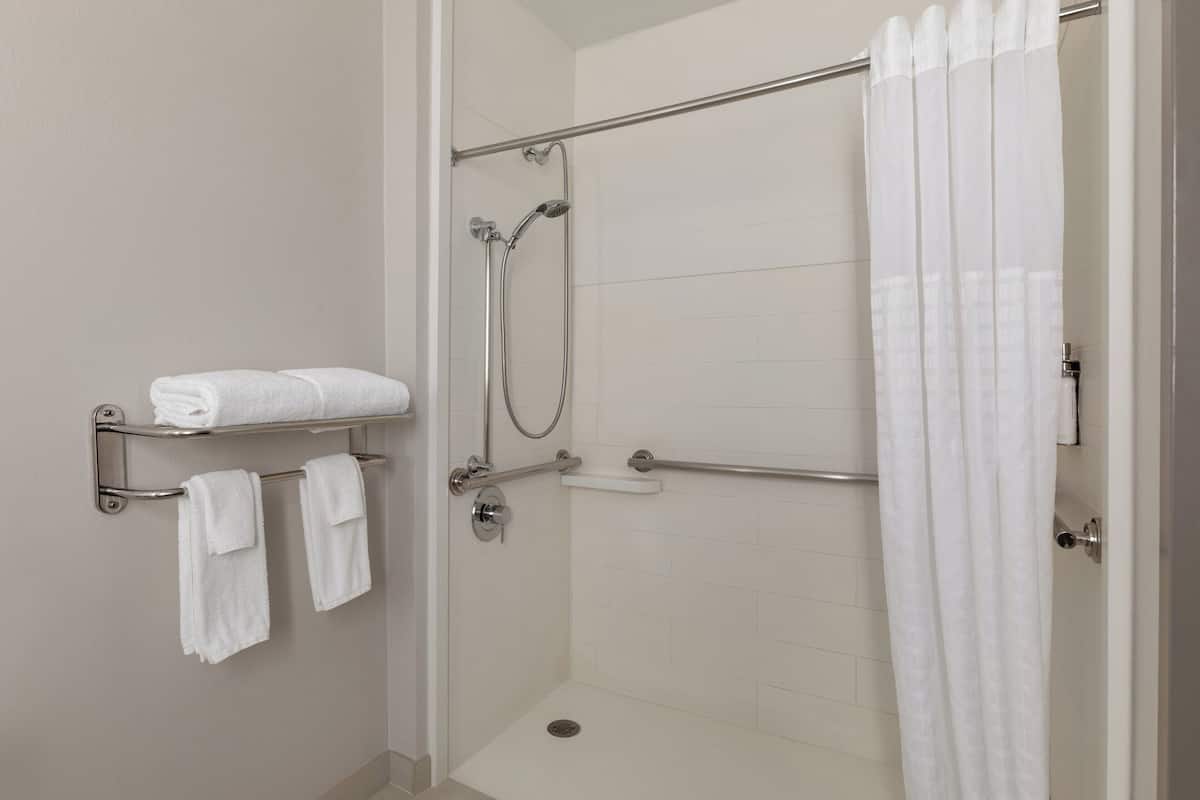 A shower with a glass door, a towel rack with folded towels, and a shower control panel.