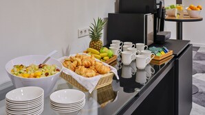 En buffet med frugt, kager og kaffekopper.