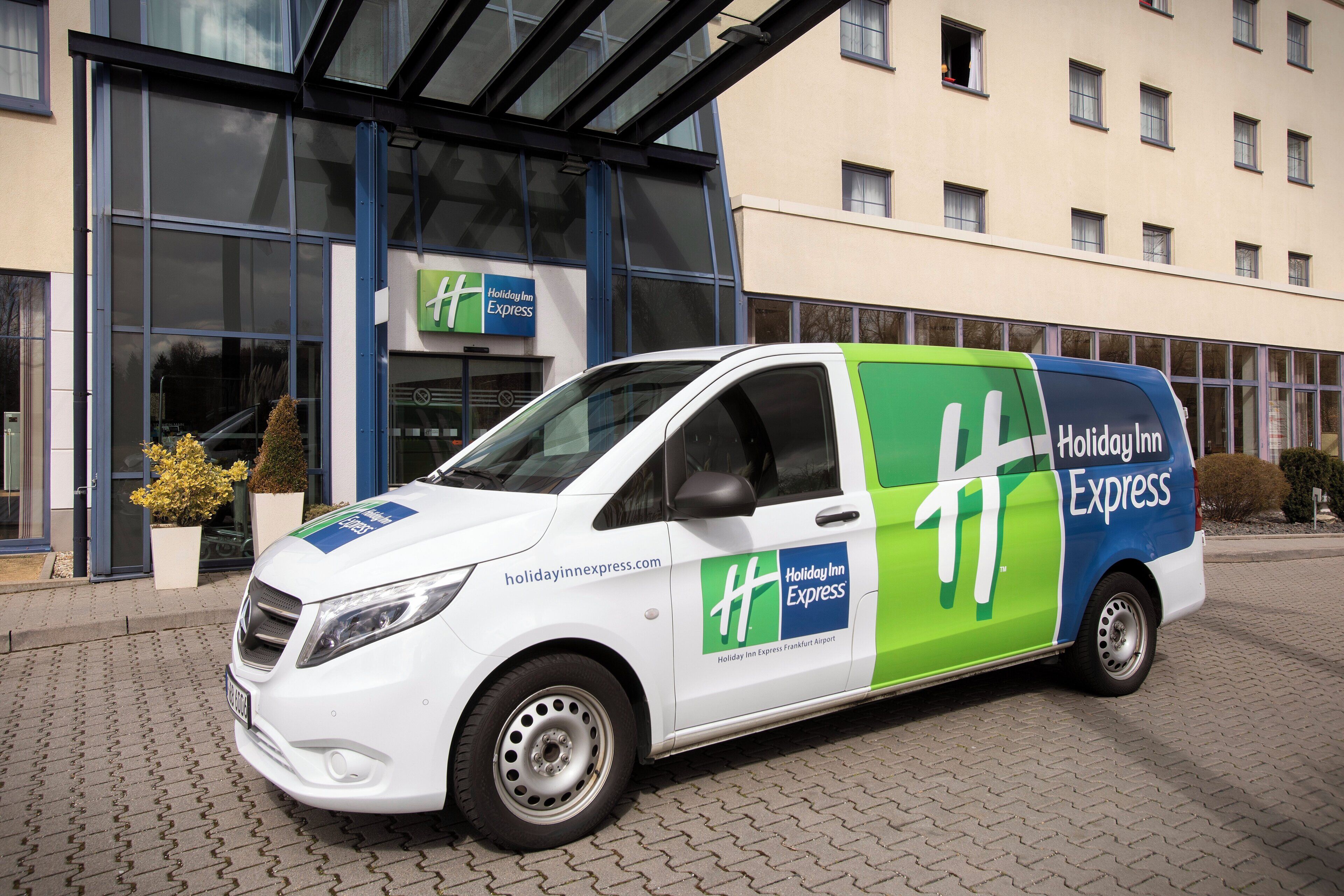 A white and green Holiday Inn Express van parked in front of the hotel.
