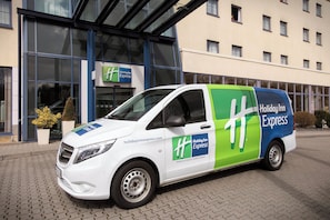 Un fourgon blanc et vert de la chaîne Holiday Inn Express était garé devant l’hôtel.