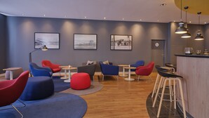Et moderne loungeområde med runde borde, farverige stole og en bar.