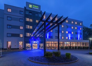 Un hôtel Holiday Inn Express doté d’une façade moderne, d’une entrée abritée et d’un espace paysager agrémenté de plantes.