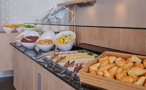 A buffet with various food items including fruits, cereals, and pastries.