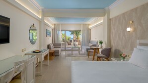 Een hotelkamer met een bed, bureau, stoel, bank en balkon met uitzicht op palmbomen en zee.