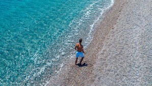 Een strand met helderblauw water en een kiezelstrand.