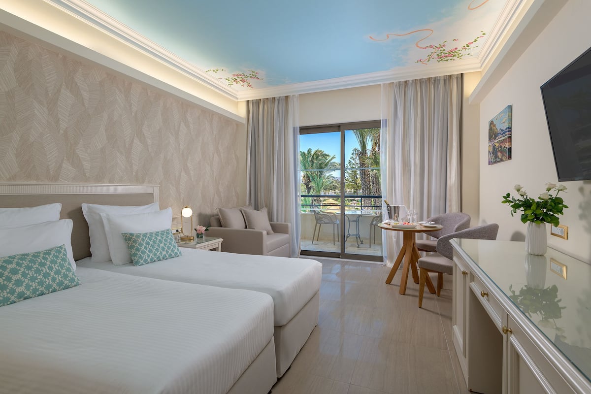 Ein Hotelzimmer mit zwei Betten, einem Essbereich und einem Balkon mit Blick.