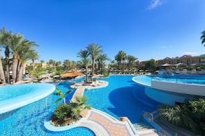 A resort pool area with palm trees, lounge chairs, and a clear blue sky. - Atrium Palace Thalasso Spa Resort & Villas (Rhodes)