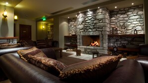 A cozy lounge area with leather sofas, a stone fireplace, and ambient lighting. - Itilo Traditional Hotel (East Mani)