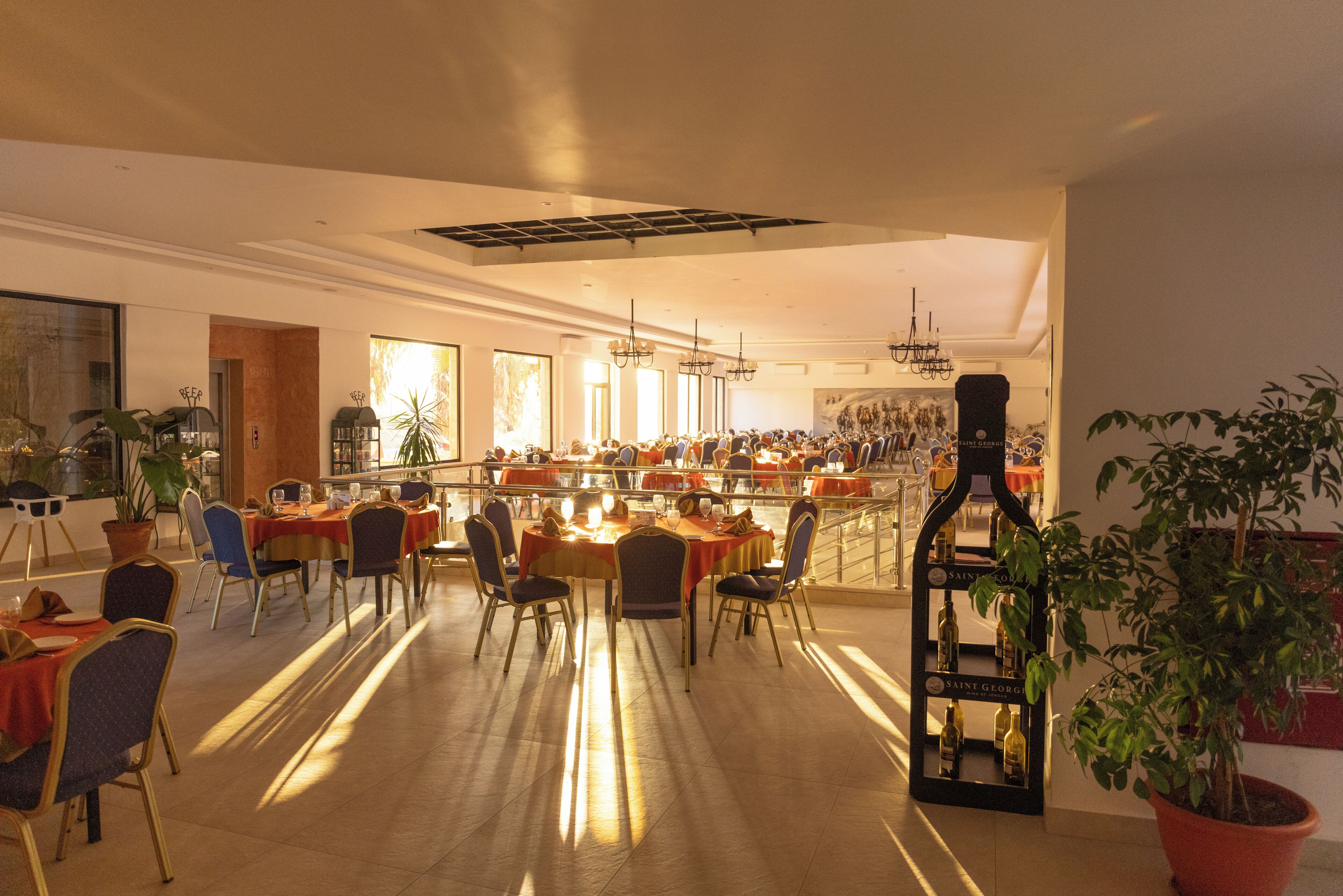 A spacious hotel lobby with multiple dining tables, chairs, and a bar area.