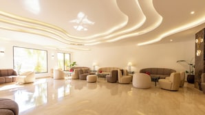 A spacious, modern living room with a polished marble floor, contemporary furniture, and a large window providing natural light. - Petra Palace Hotel (Wadi Musa)