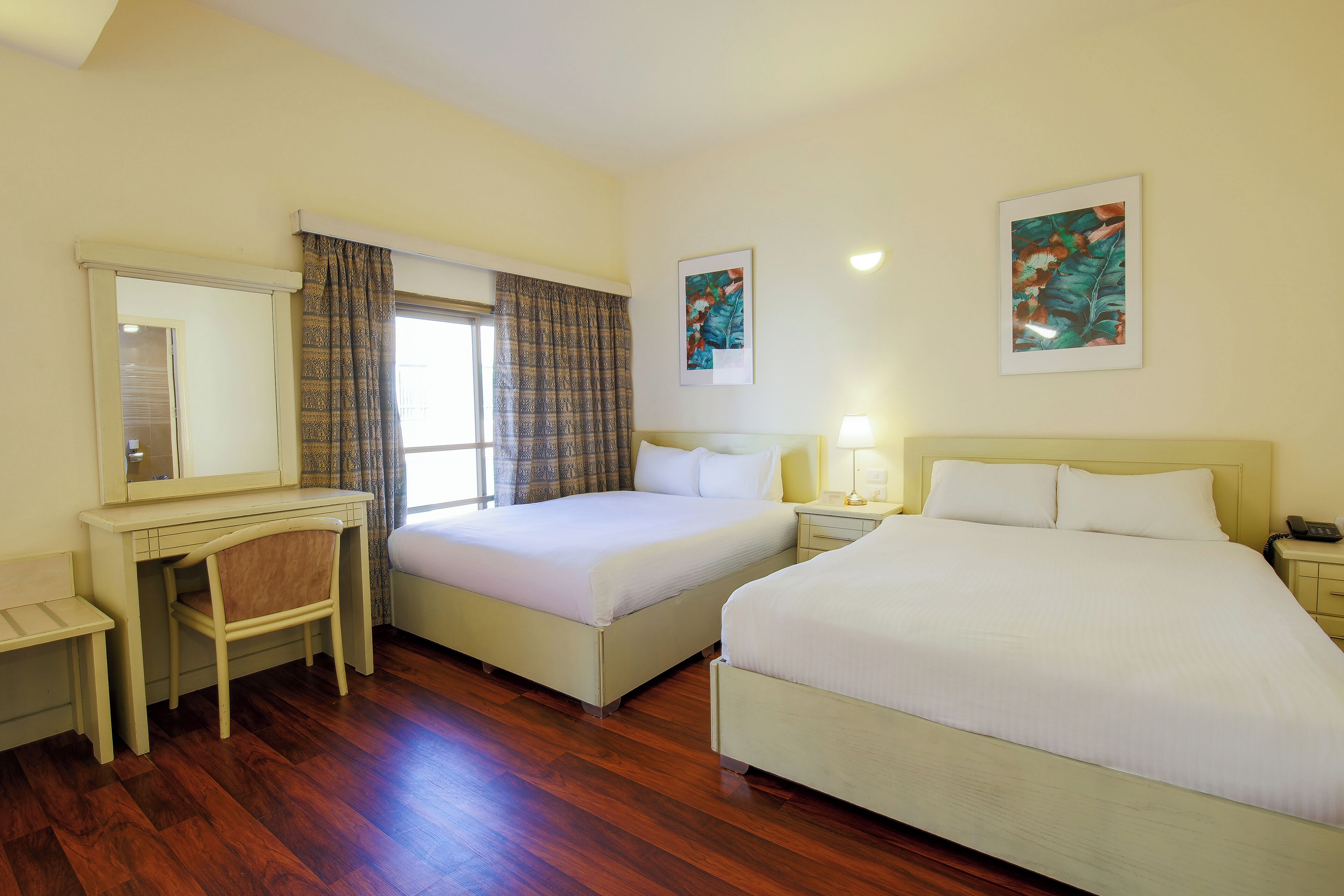 A hotel room with two beds, a desk, and a chair.