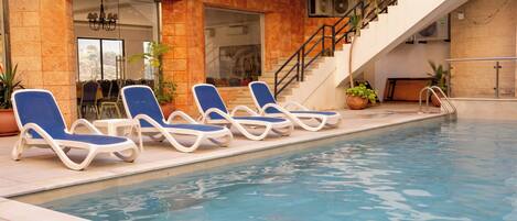 A swimming pool with lounge chairs and a staircase leading to an upper level.