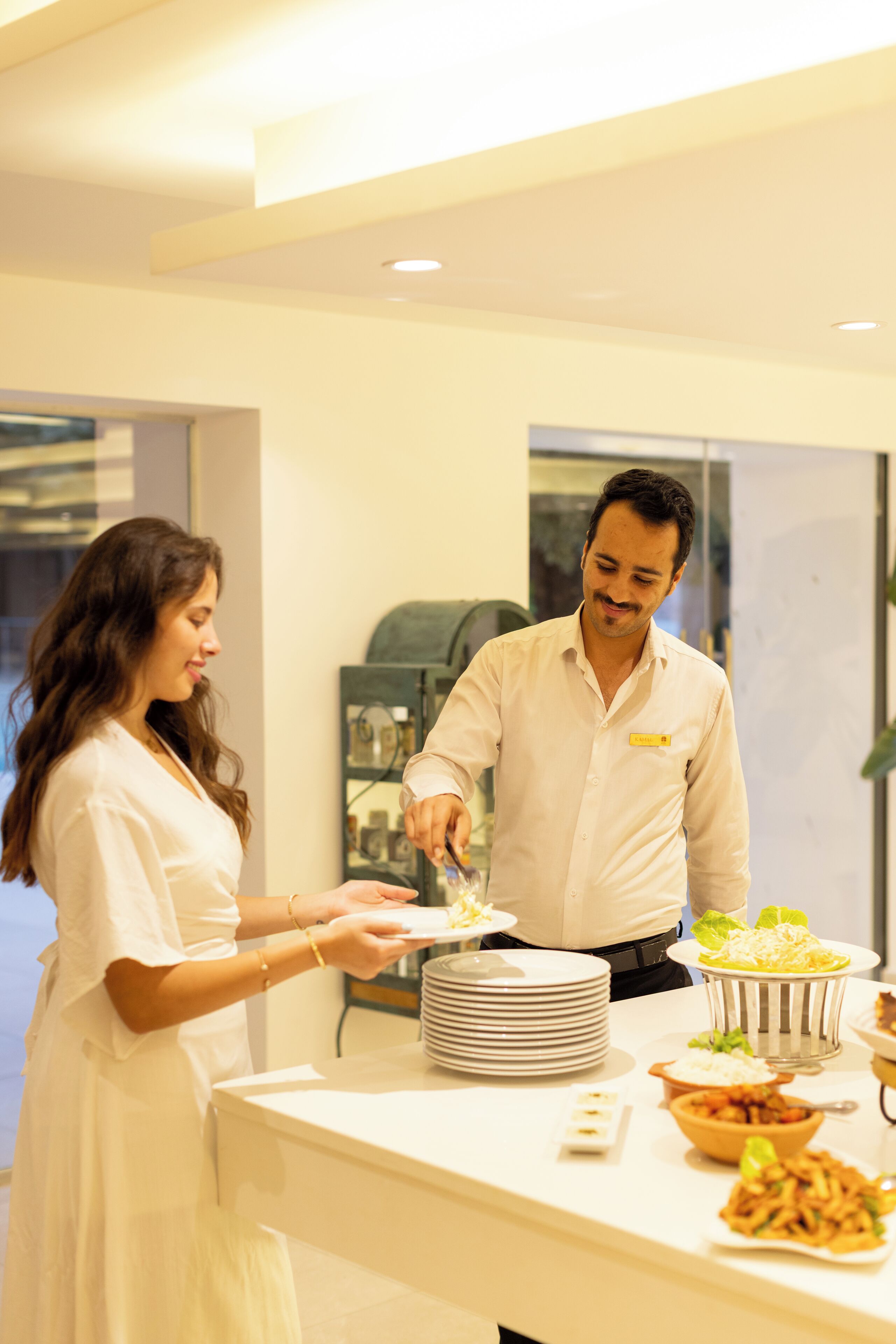 A buffet setup with various dishes and a person serving food.
