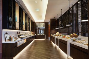 Un hall d’hôtel moderne avec un long comptoir d’accueil, un plancher en bois et un éclairage décoratif.
