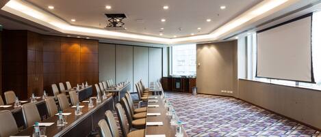 A conference room with a long table, chairs, and a projector screen.