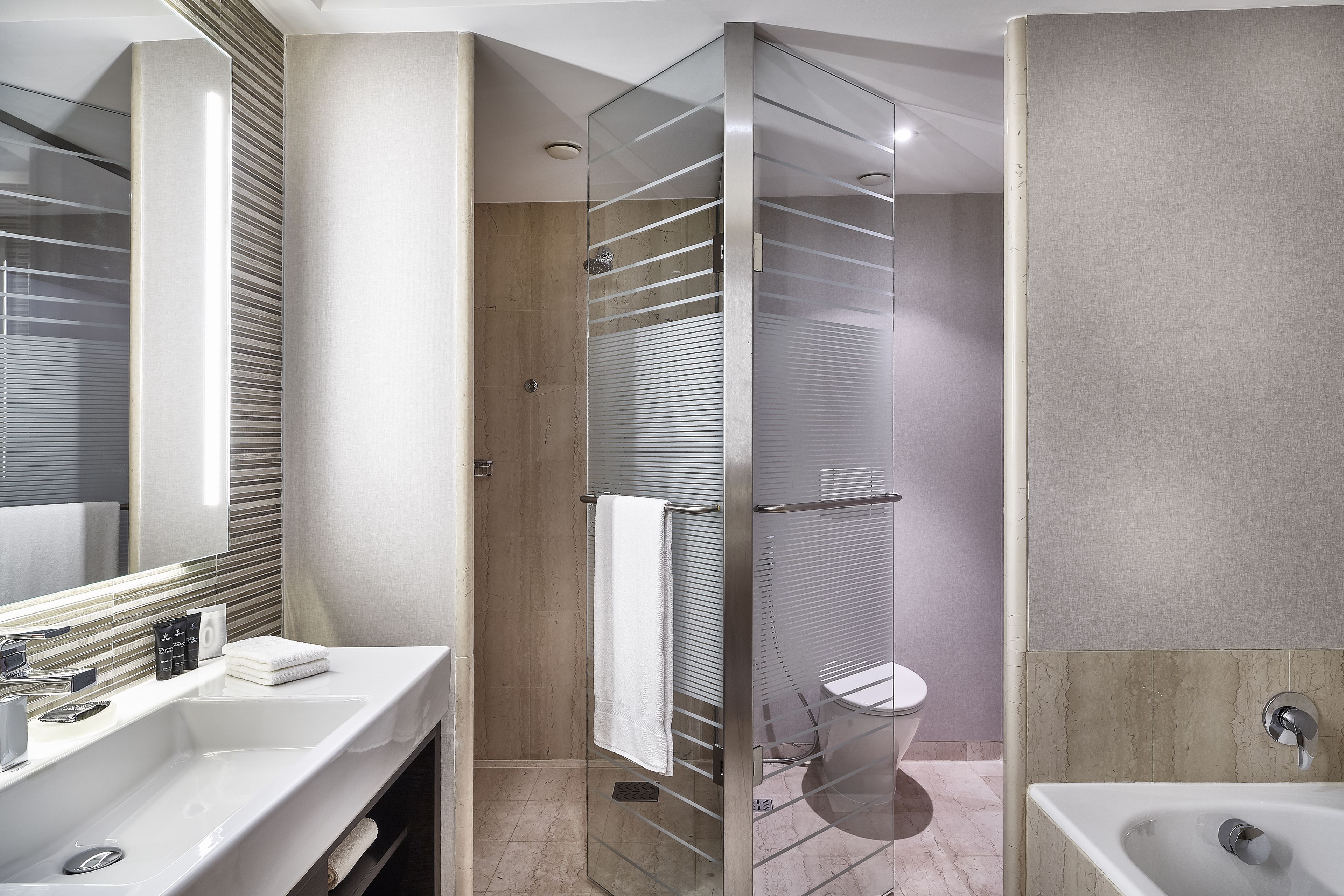 A modern bathroom with a glass-enclosed shower, a large mirror, and a separate sink area.