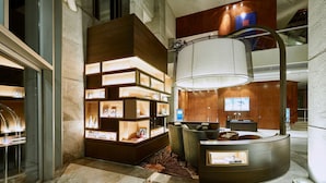 A modern lobby with a central seating area, a large decorative light fixture, and a display of framed pictures.